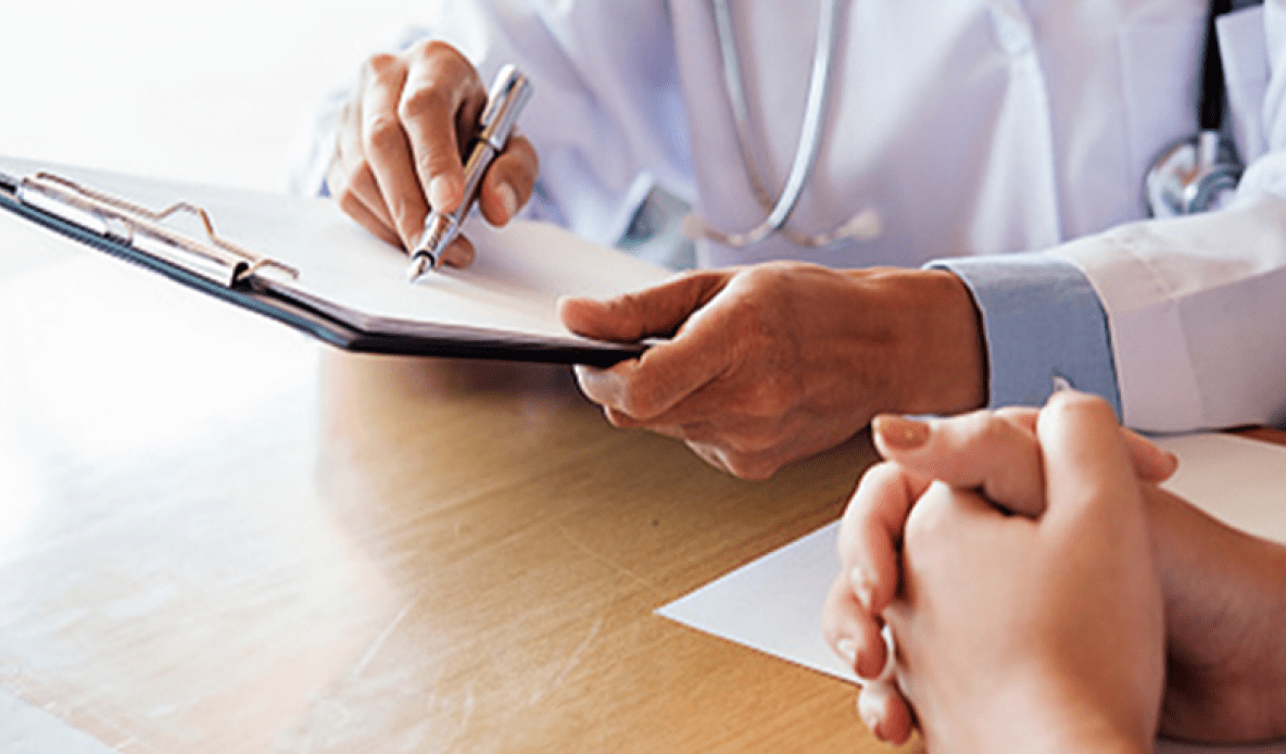 Close-up of a doctor holding a pen over a clipboard during a consultation