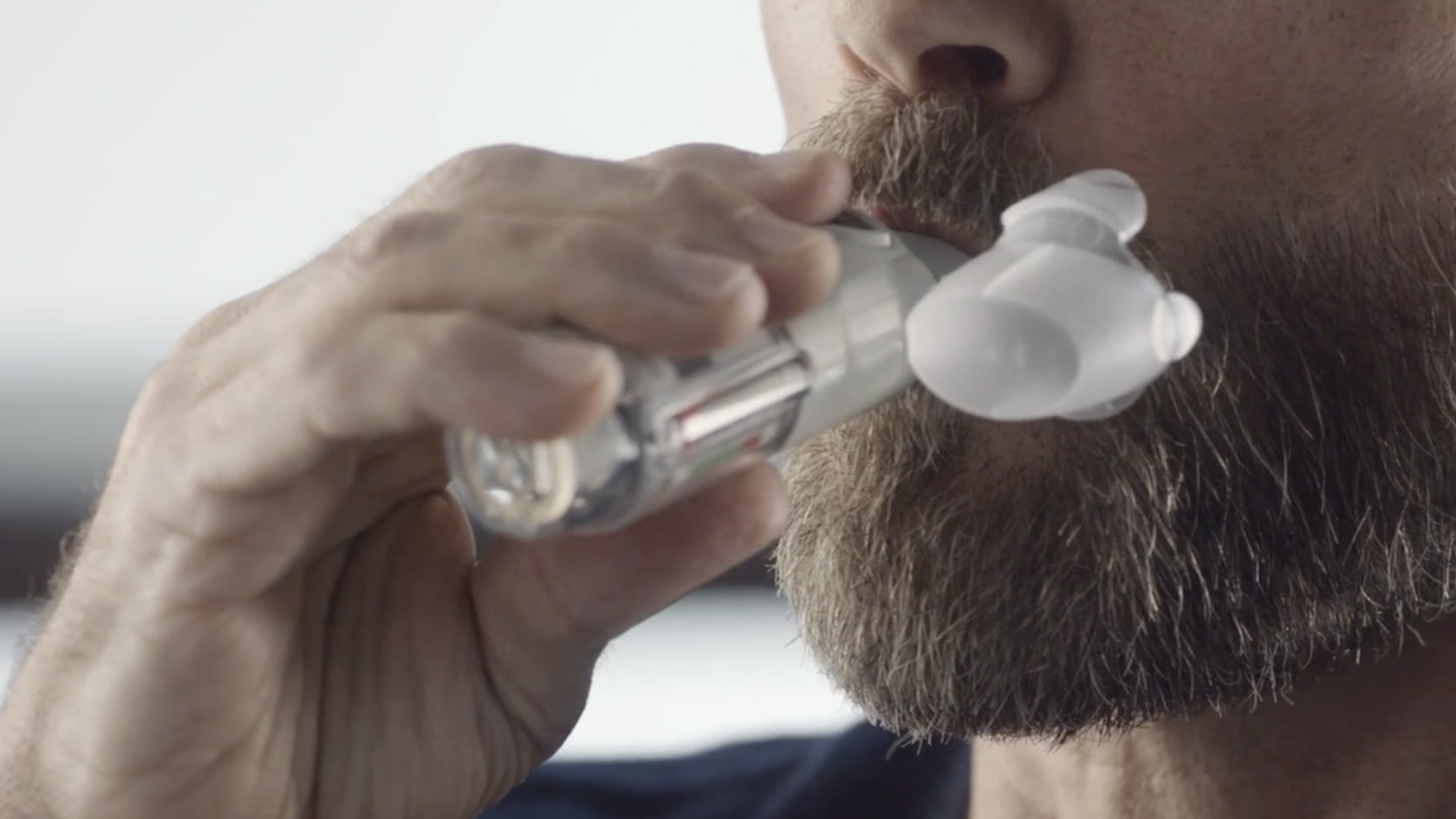 Man placing the Spiriva Respimat mouthpiece in his mouth to inhale the dose