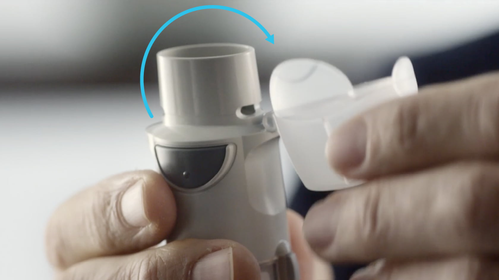Hand opening the protective cap of a Spiriva Respimat inhaler to expose the mouthpiece