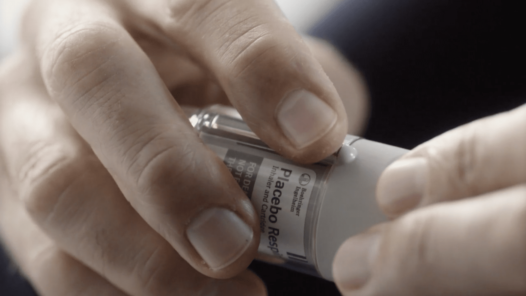 Finger pressing the safety catch button on the side of a Spiriva Respimat inhaler